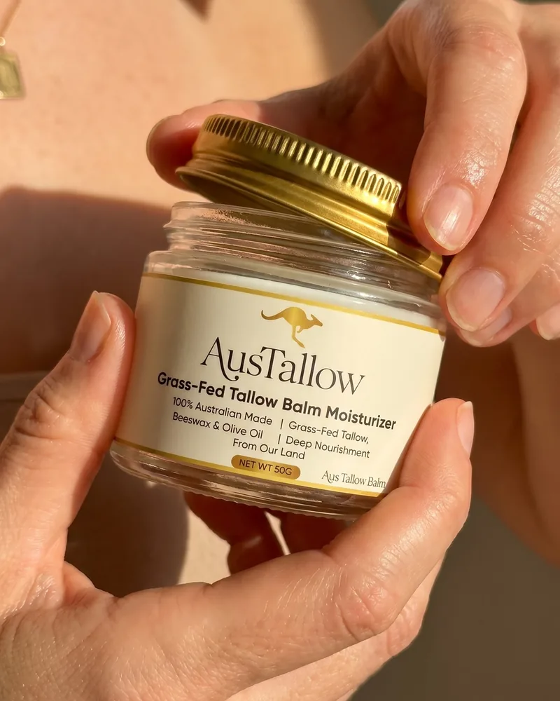 Hands opening a jar of AusTallow grass-fed tallow balm in natural light