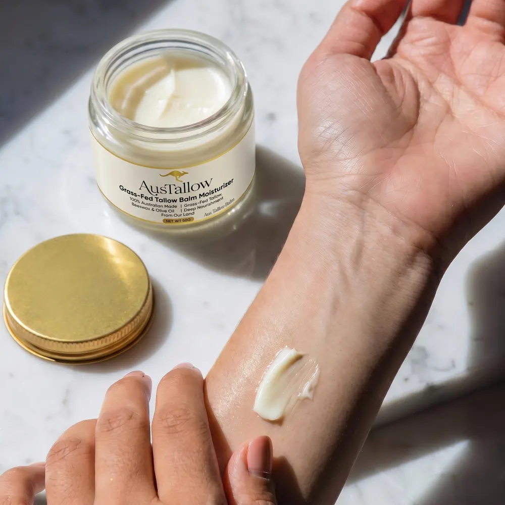 A swatch of AusTallow balm absorbing into the back of a hand beside the open jar